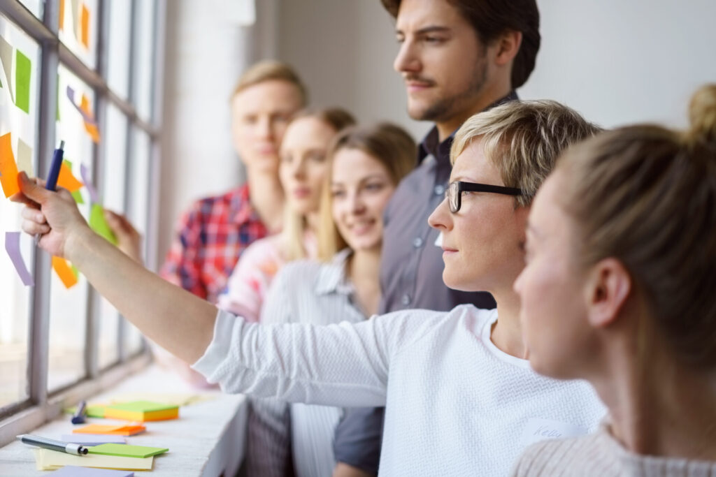 Team erarbeitet Ideen und klebt Zettel an ein Fenster