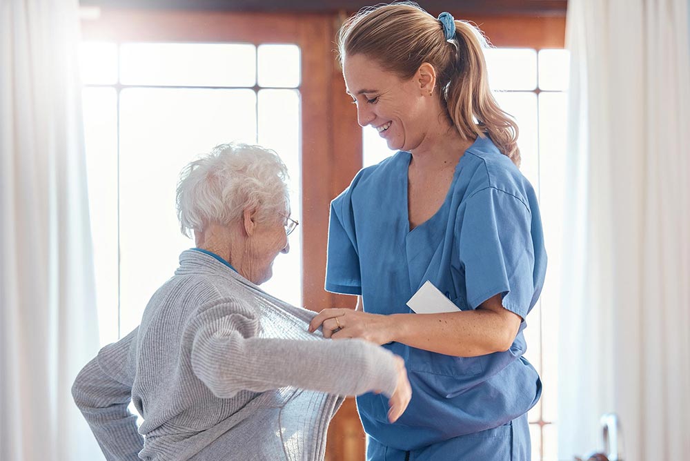 Pflegerin hilft Seniorin beim Ankleiden